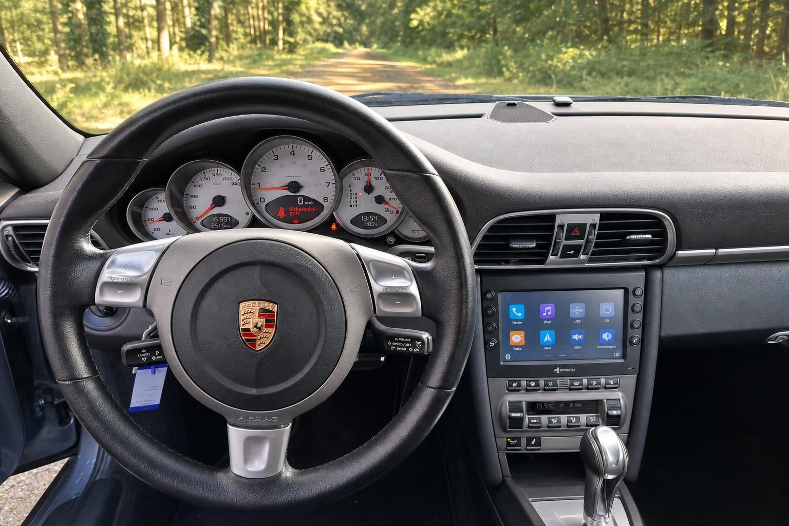 Porsche Cockpit mit Lenkrad, Rundinstrumenten und modernem Infotainment-Display in der Mittelkonsole