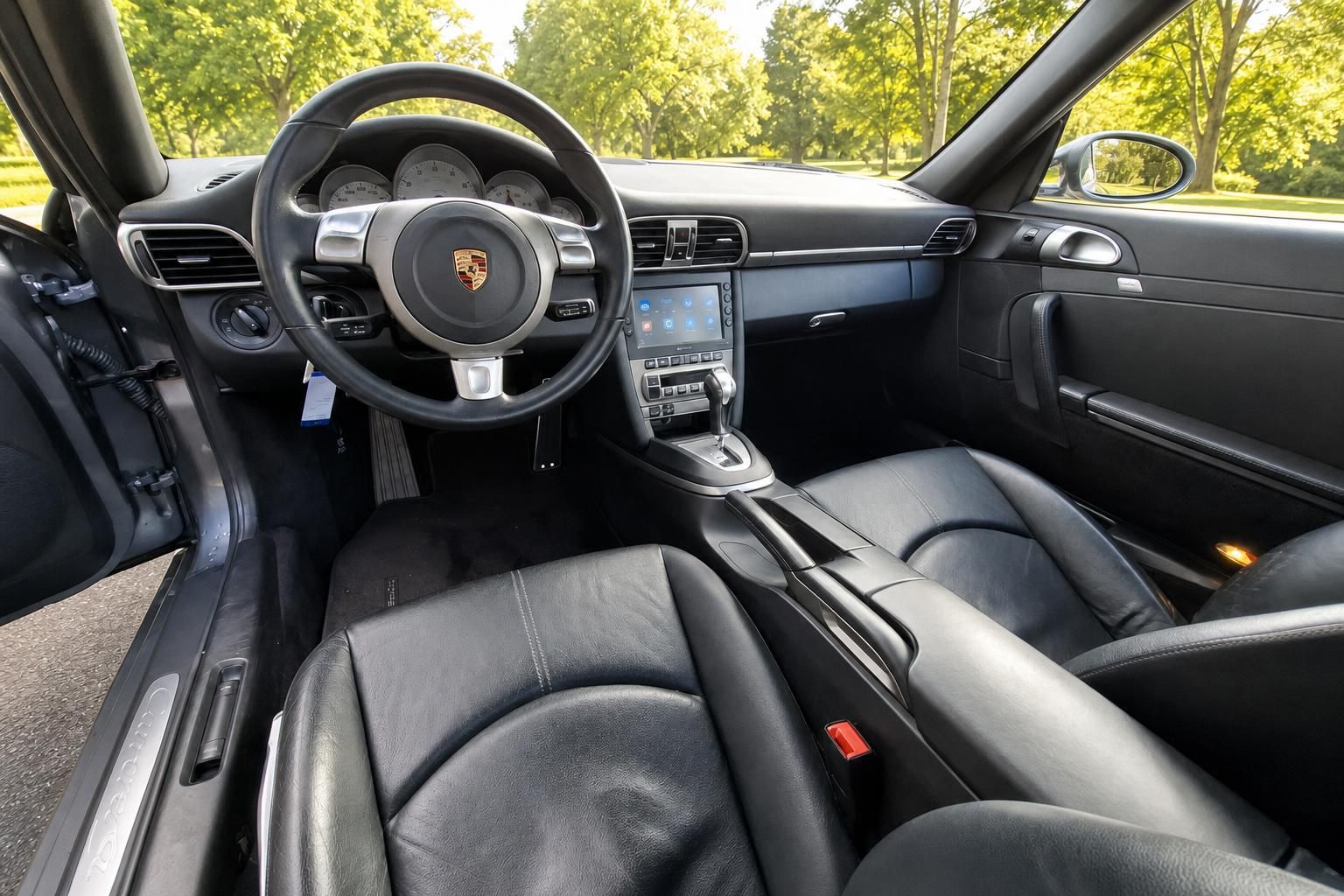 Porsche Innenraum mit schwarzem Leder, Lenkrad mit Porsche-Logo und Mittelkonsole mit Touchscreen