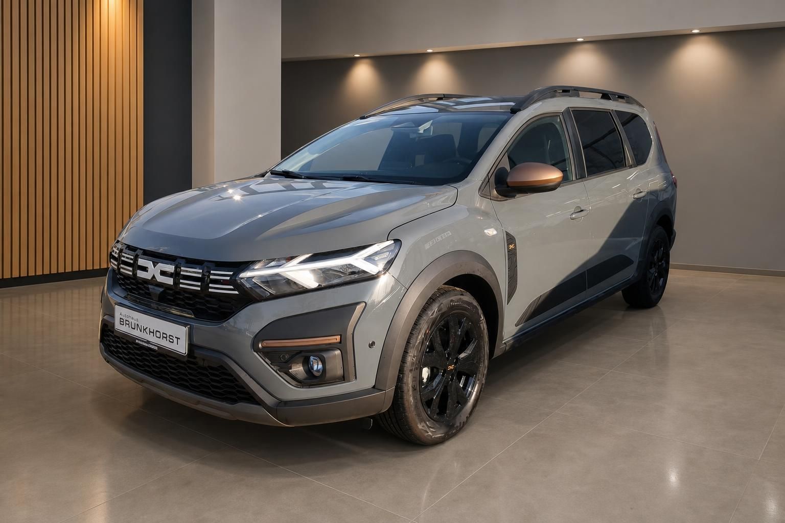 Dacia SUV in grau im modernen Autohaus-Showroom - Seitenansicht des Fahrzeugs mit schwarzen Felgen