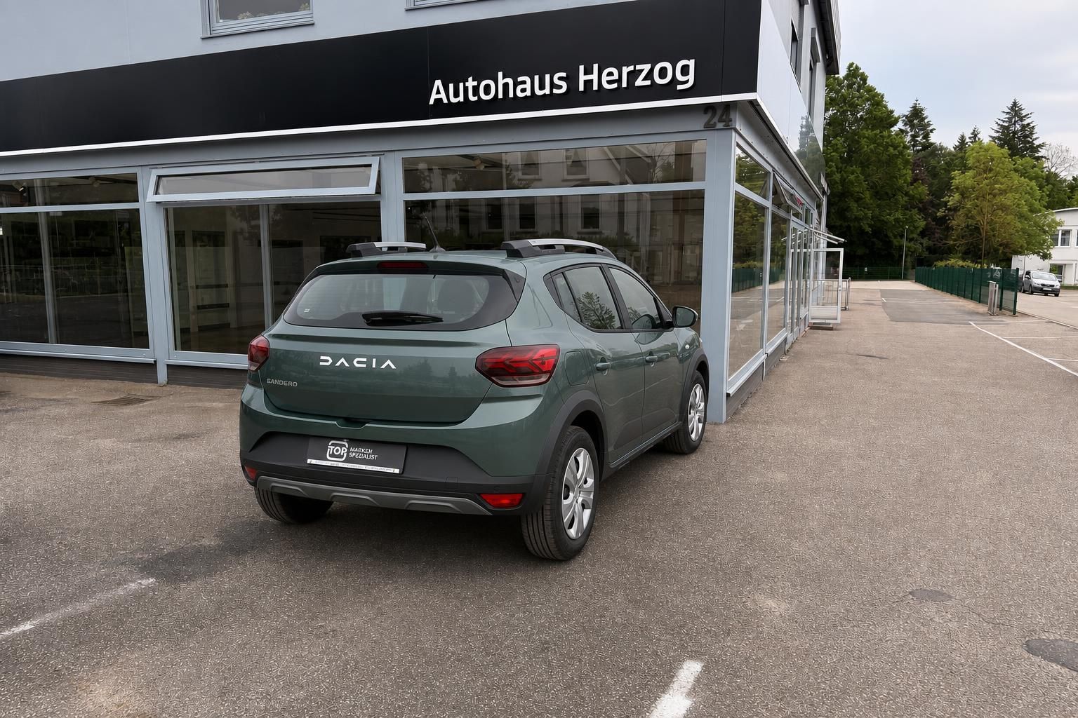Dacia Sandero grün metallic Rückansicht schräg vor Autohaus Showroom