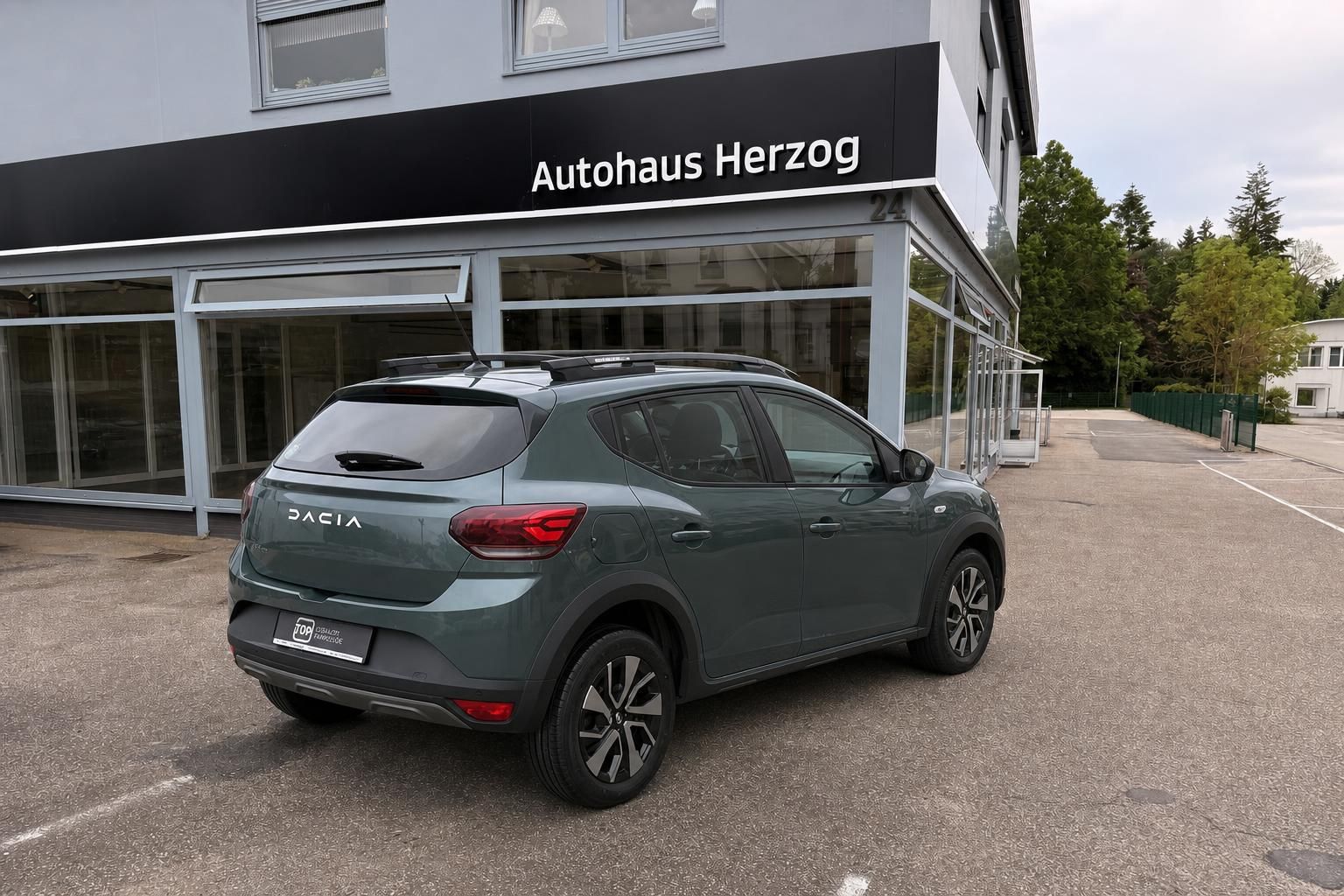 Dacia Sandero grün metallic Heckansicht schräg vor Autohaus Herzog