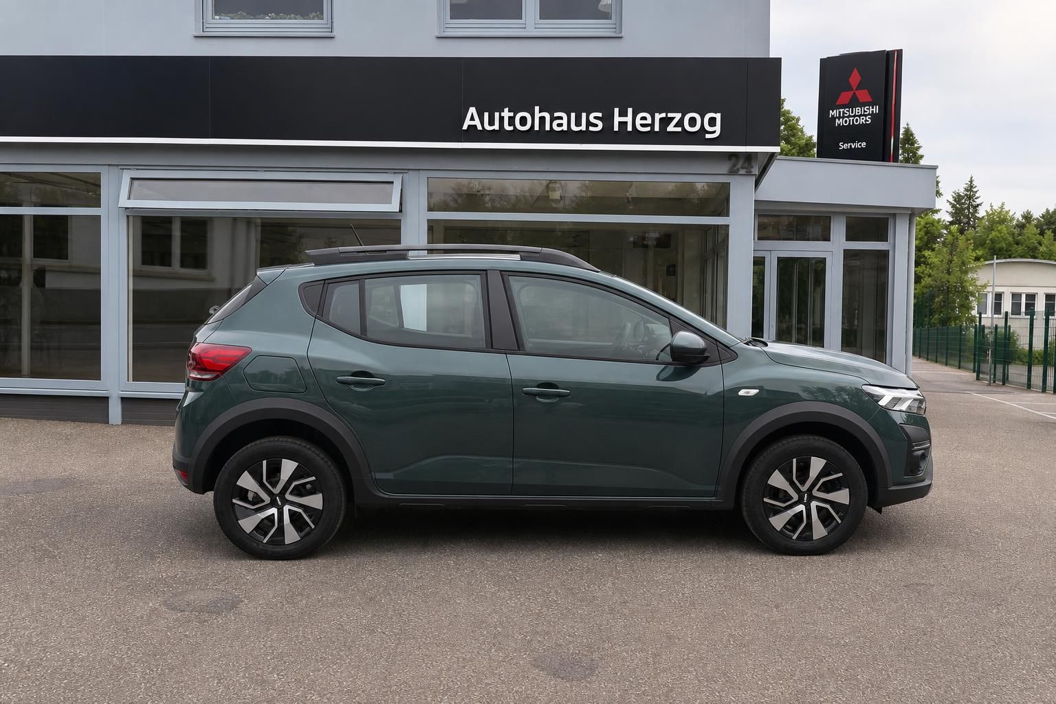 Grauer Dacia Stepway SUV Seitenansicht vor Autohaus Herzog - moderner Crossover mit Dachreling