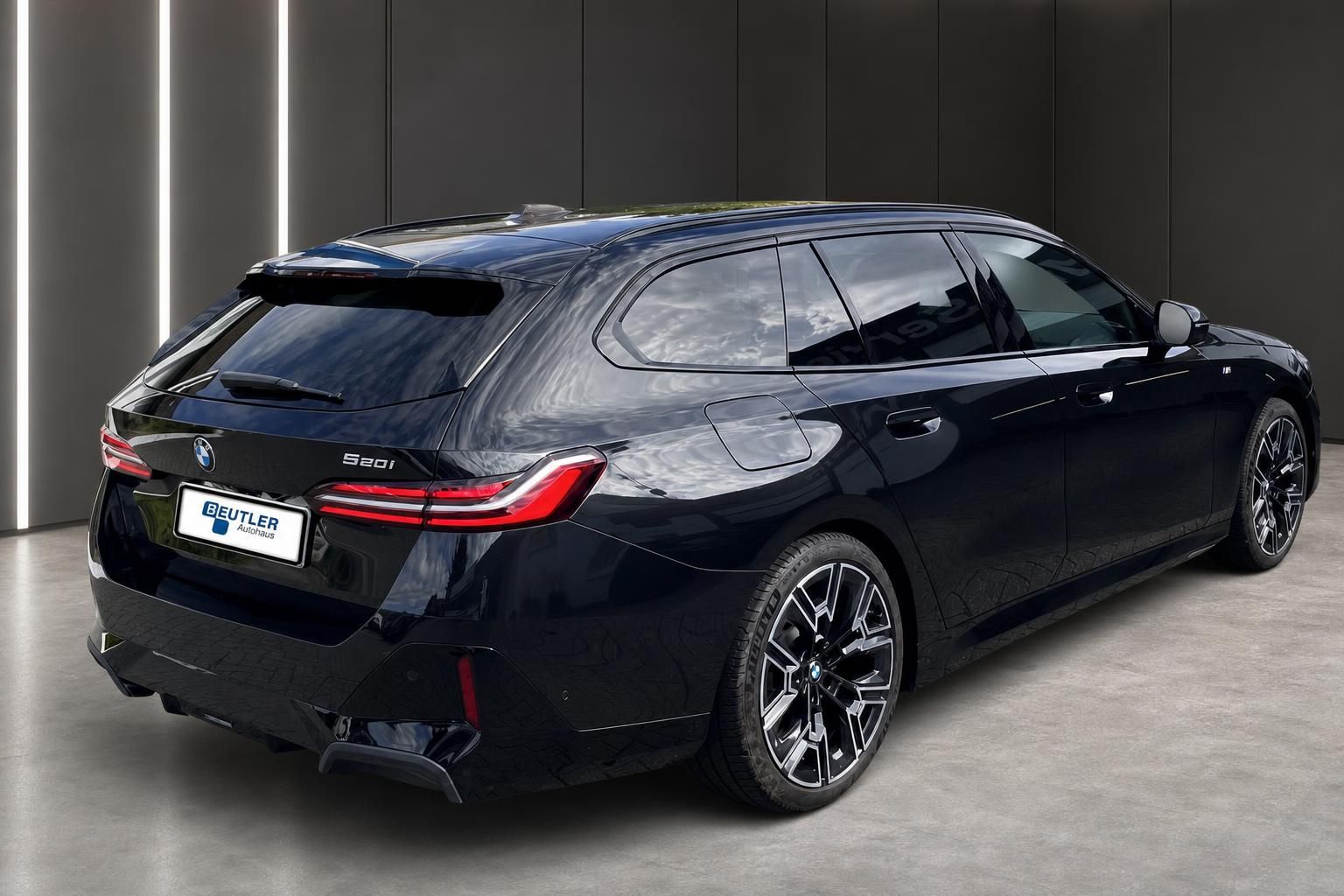 BMW 5er Touring 520i schwarz, Heckansicht seitlich in Ausstellungshalle