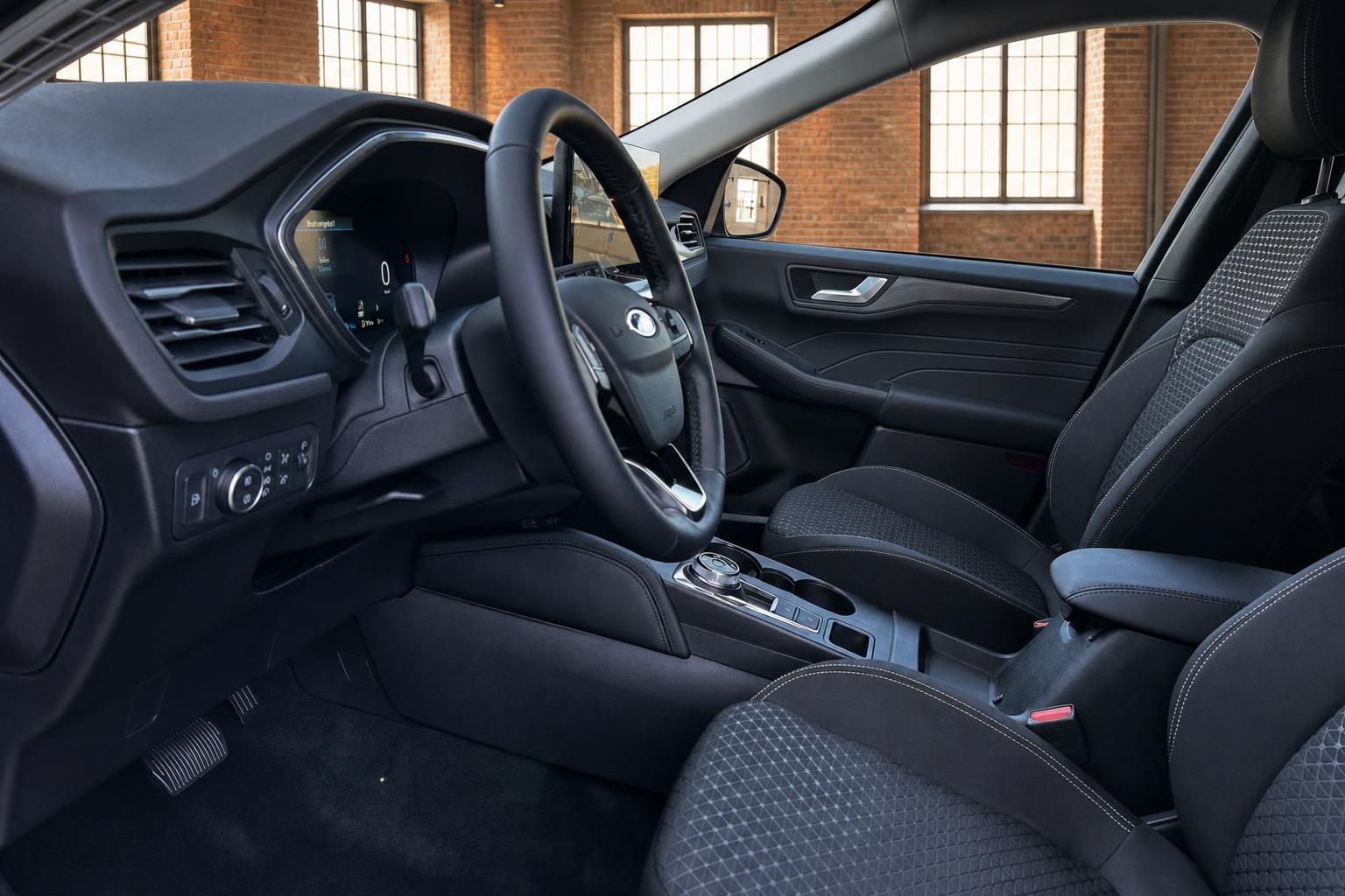 Ford Kuga Innenraum Fahrerseite mit Lenkrad, Mittelkonsole und schwarzen Sitzen