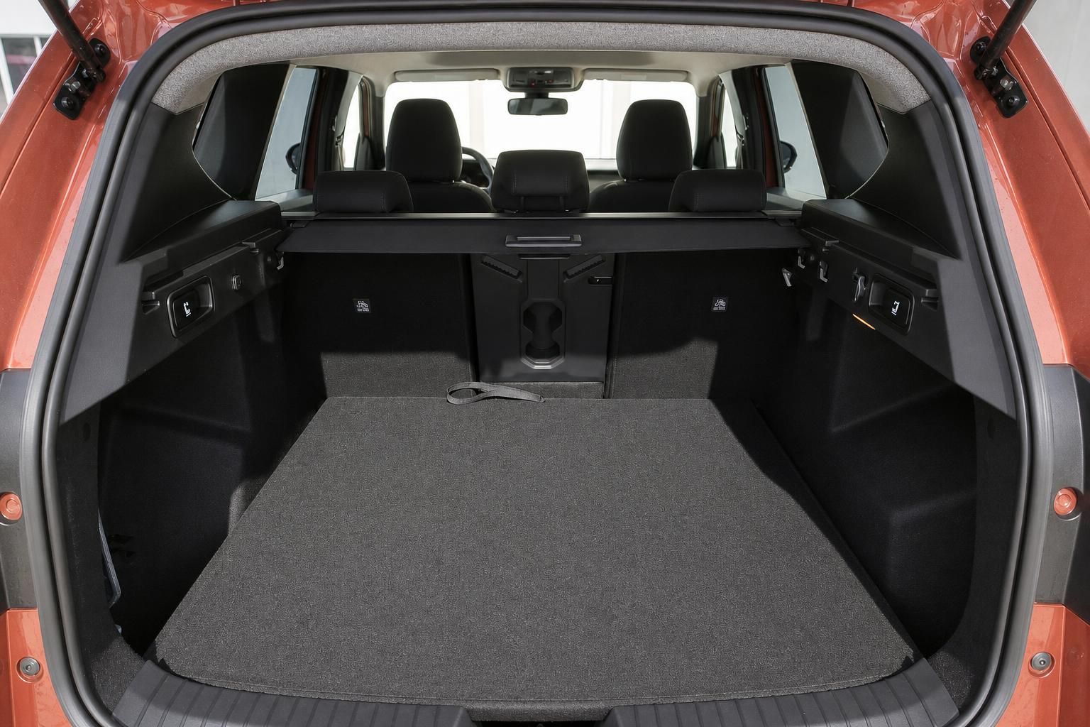 Kofferraum eines orangefarbenen Kombi mit umgeklappten Rücksitzen, Blick nach vorne