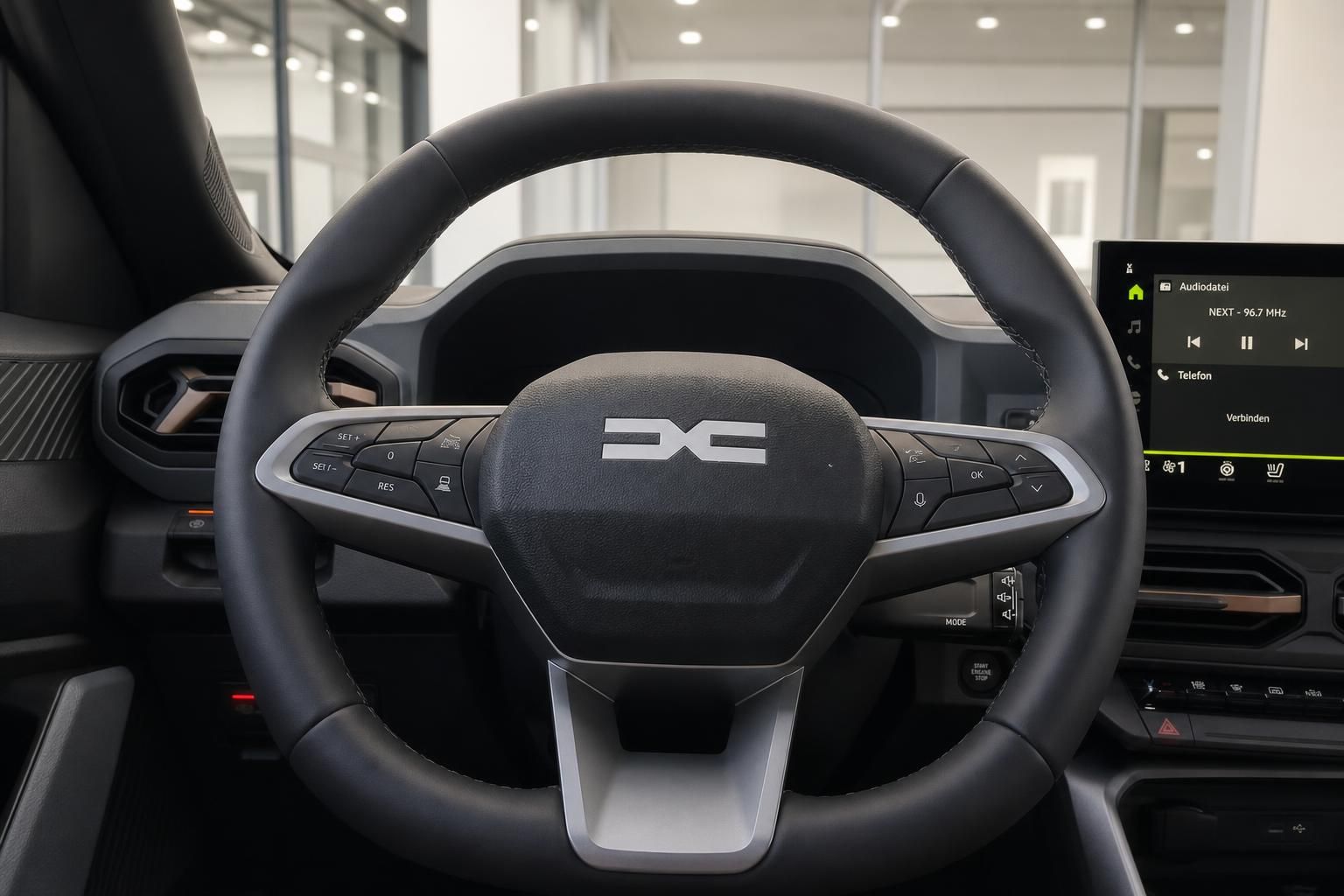 Lenkrad mit Multifunktionstasten und Infotainment-Display im Fahrzeuginnenraum