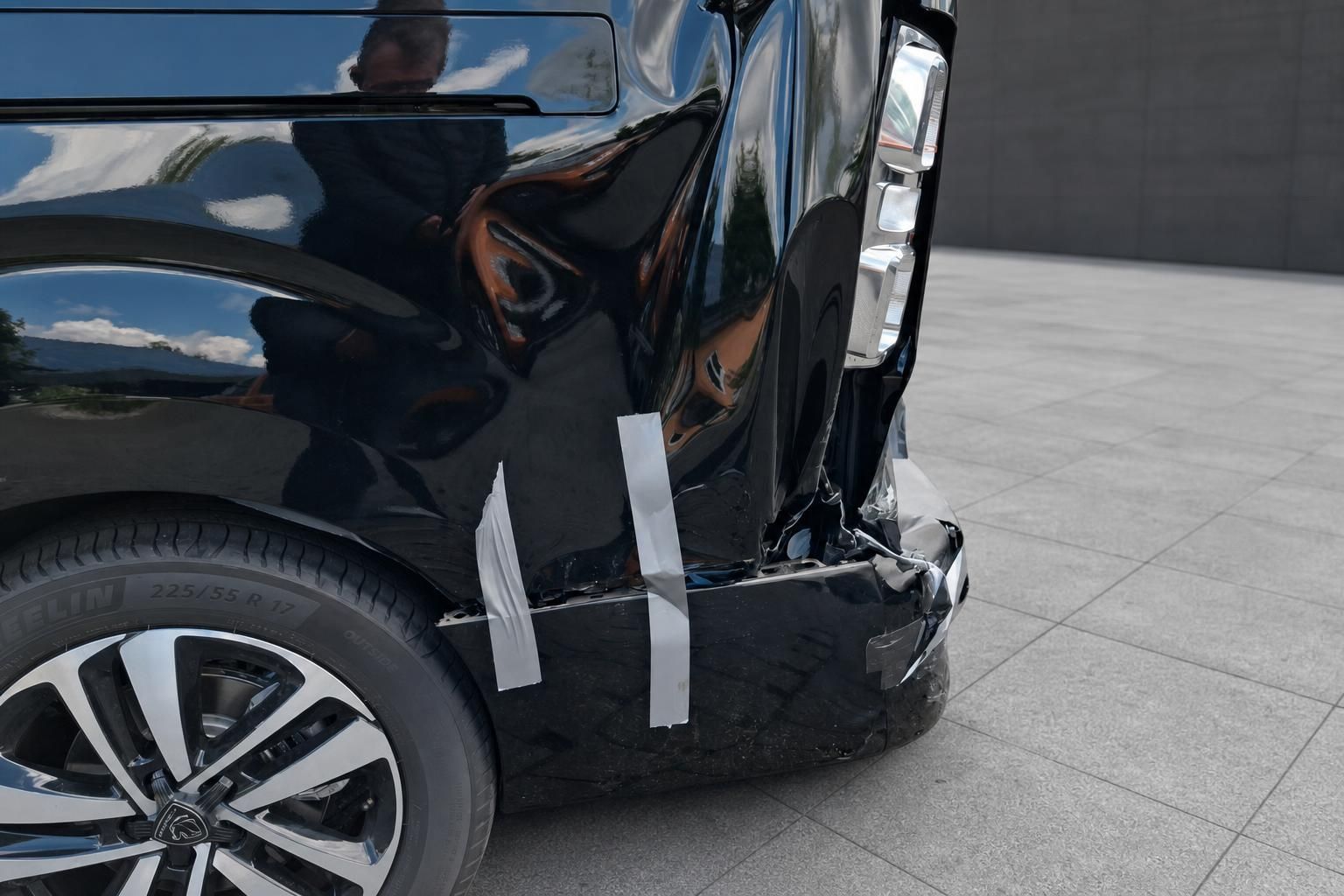 Seitliche Detailansicht der Unfallschäden am schwarzen Peugeot Traveller Van