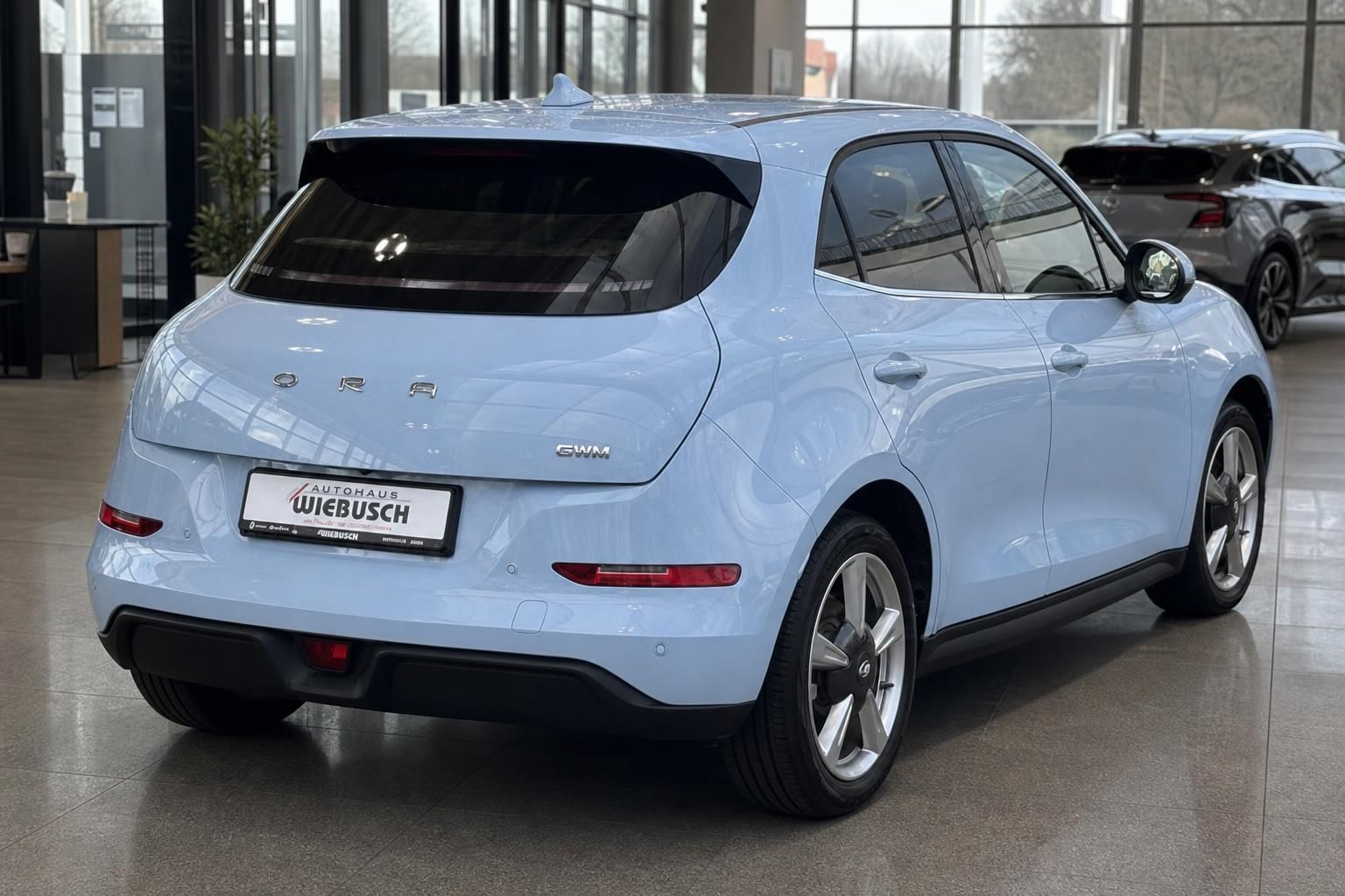 Hellblauer ORA Elektro-SUV Heckansicht schräg im Autohaus-Showroom