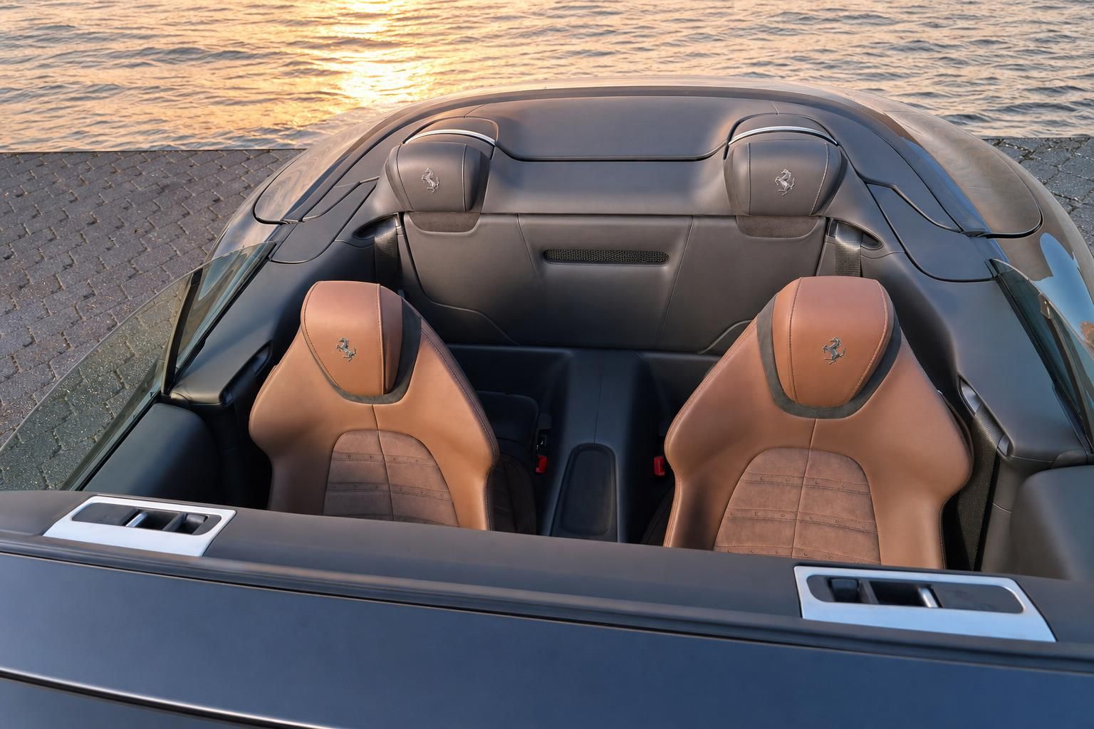 Ferrari Cabrio Sitze in Braun und Grau mit Ferrari-Logo - Blick von hinten bei Sonnenuntergang
