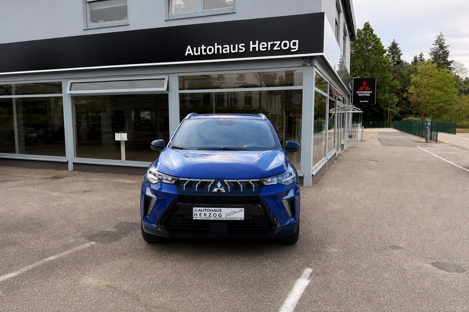 Blauer Mitsubishi SUV vor Autohaus Herzog - Frontansicht des geparkten Fahrzeugs