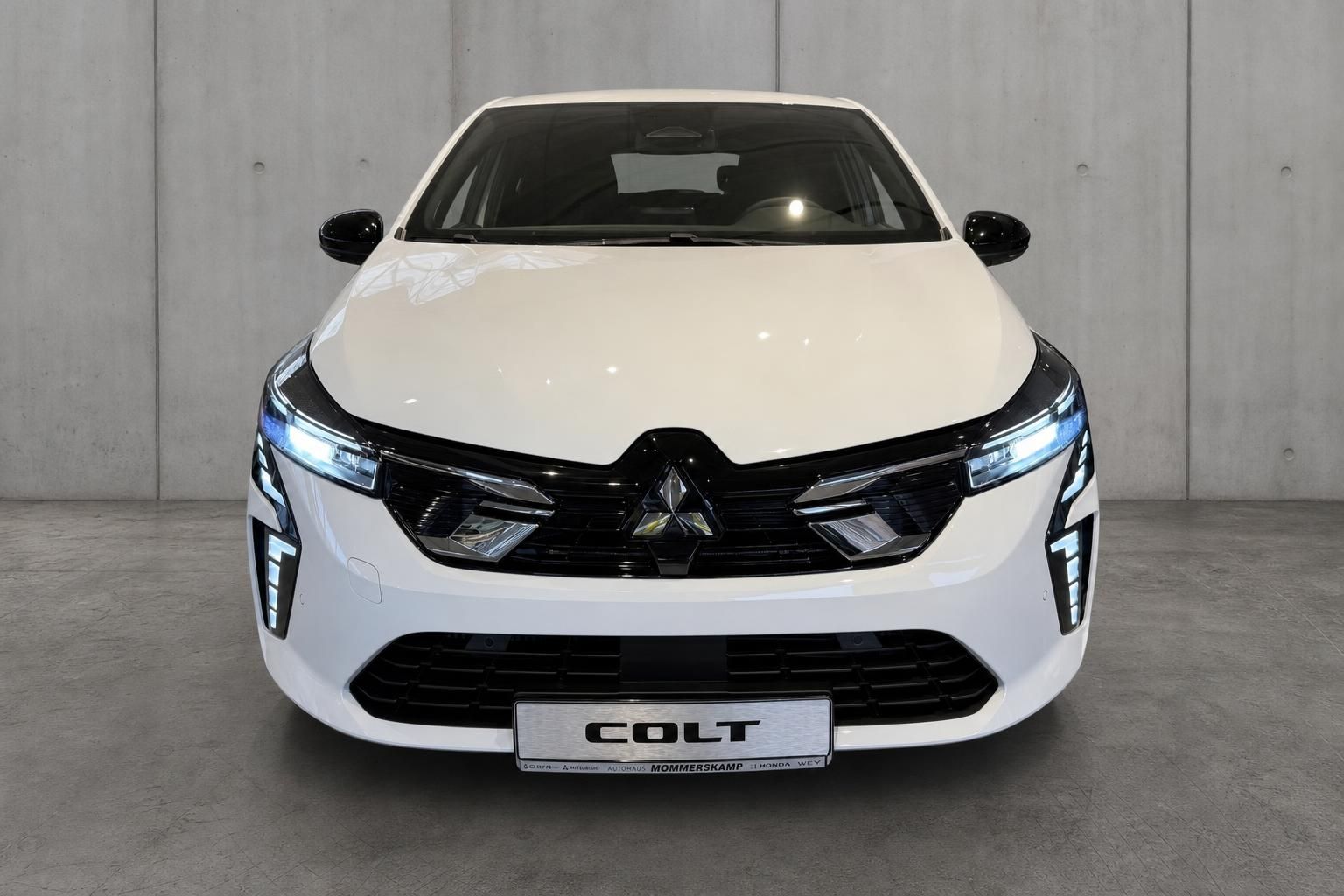 Mitsubishi Colt in Weiss von vorne mit LED-Scheinwerfern im Studio