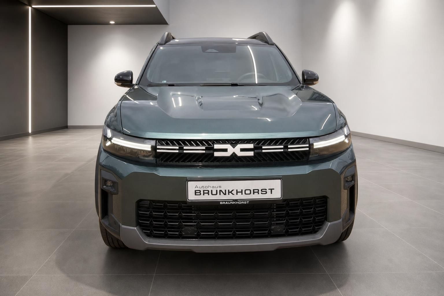 Dacia SUV Frontansicht in grau-grüner Metallic-Lackierung im Autohaus Brunkhorst Showroom