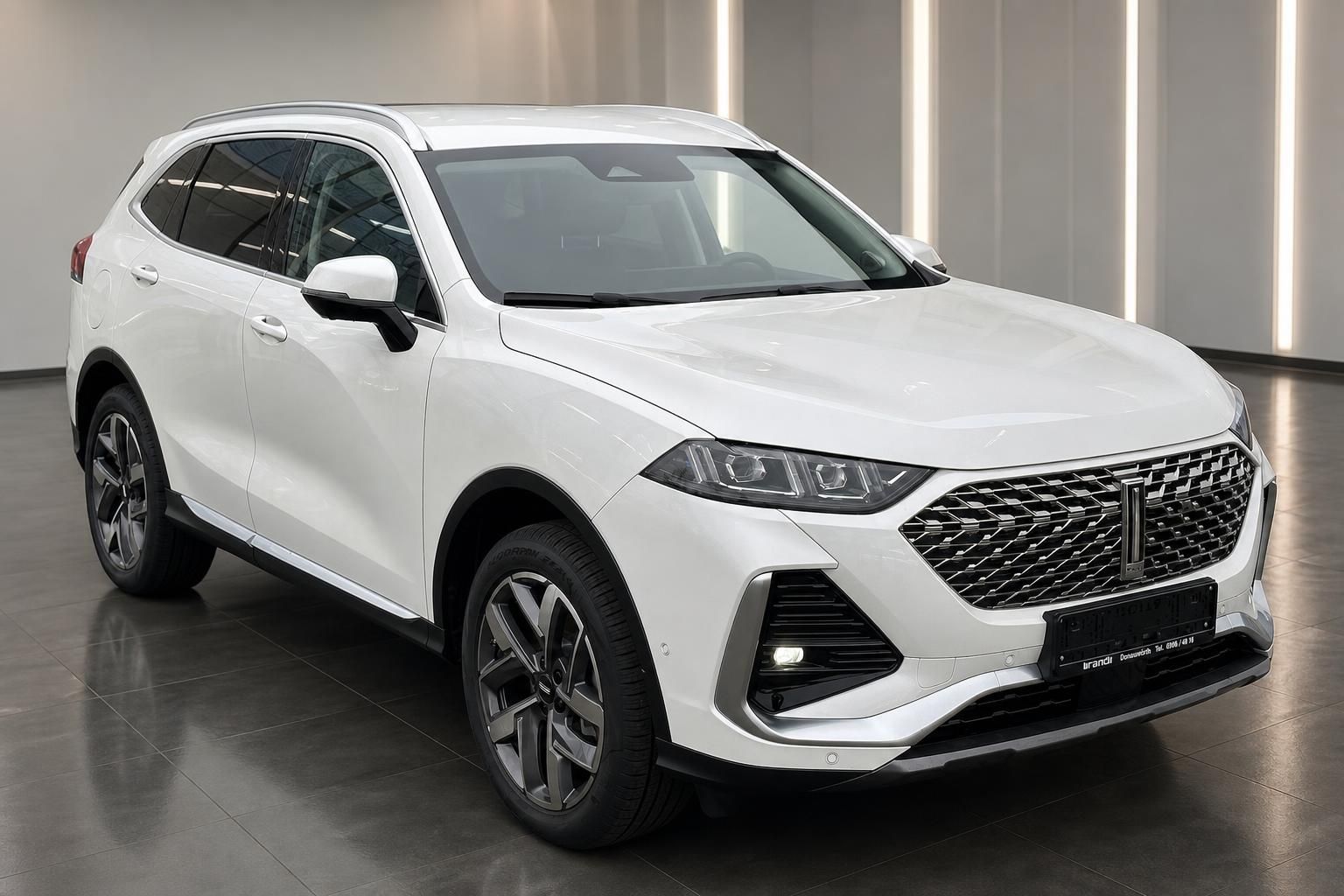 WEY SUV weiss Frontansicht schraeg rechts im Showroom mit Chromgrill und Alufelgen