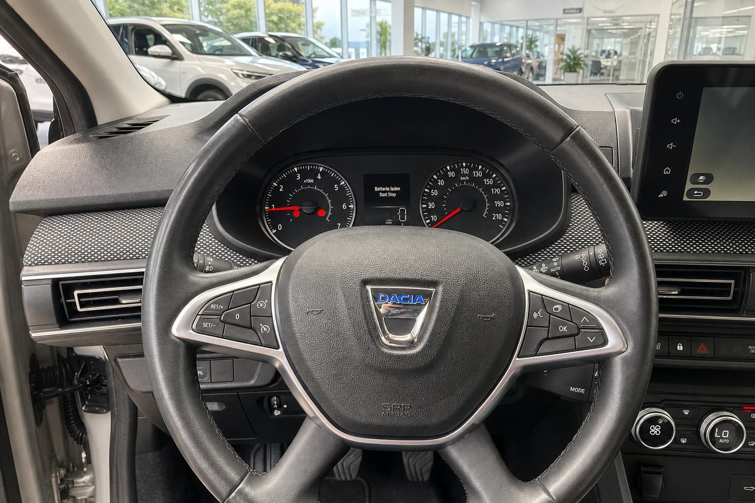 Lederlenkrad mit Bedienelementen und Dacia Logo im Innenraum