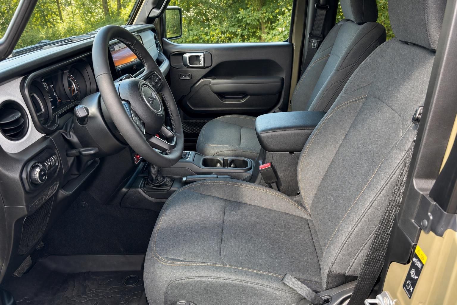 Jeep Wrangler Innenraum mit schwarzem Lenkrad, Armaturenbrett und grauen Stoffsitzen