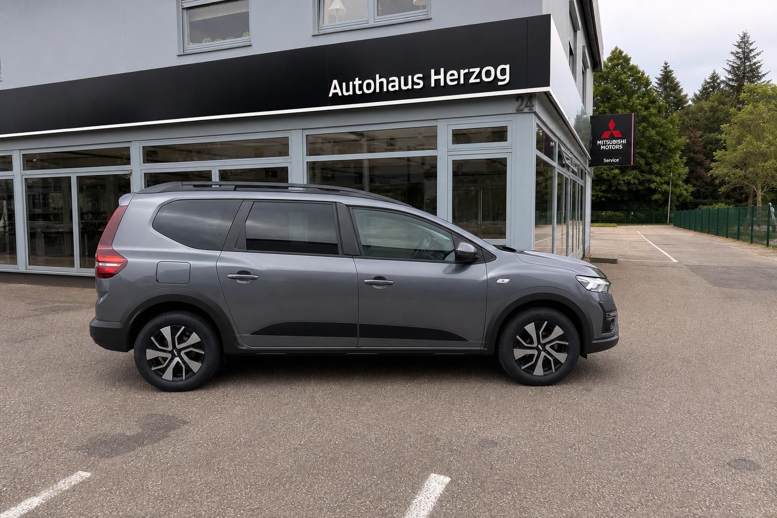 Grauer Dacia SUV Seitenprofil bei Autohaus Herzog - 7-Sitzer Familienauto mit Dachreeling