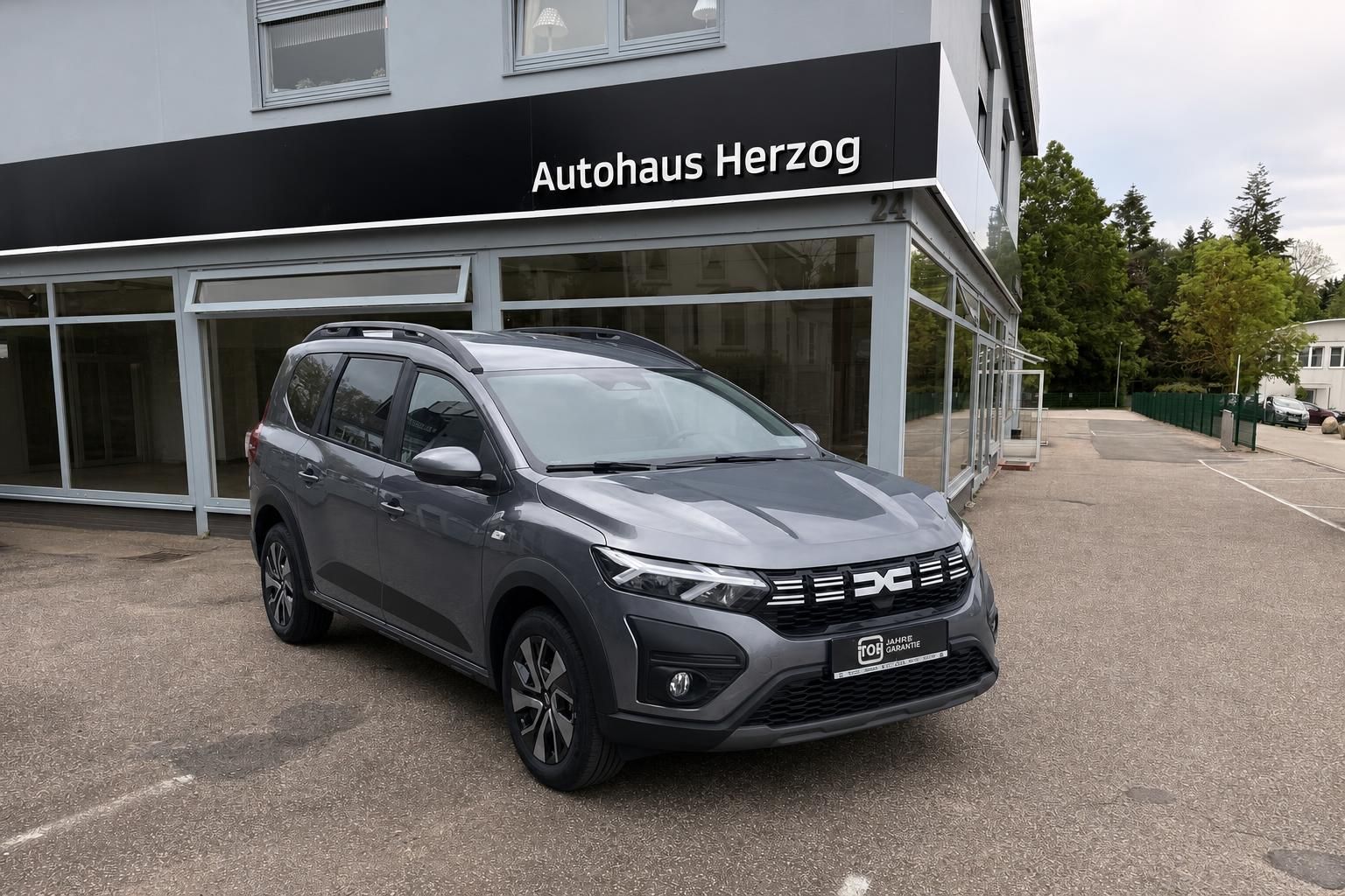 Grauer Dacia SUV Seitenansicht vor Autohaus Herzog - Gebrauchtwagen mit modernem Design