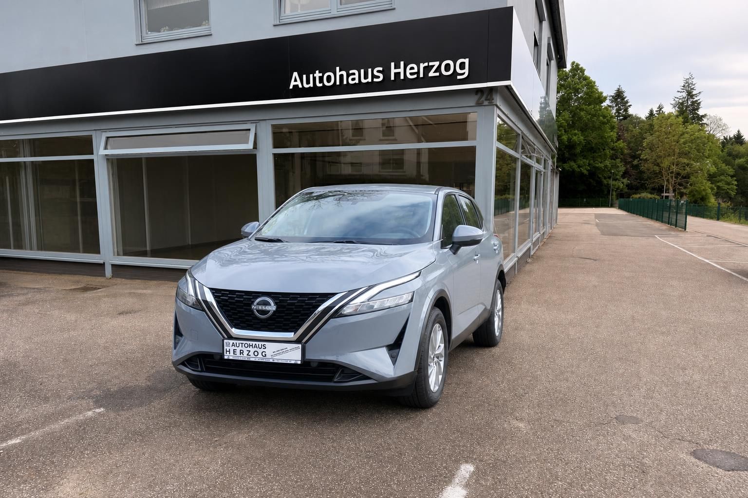 Nissan Frontansicht grau mit V-Motion-Grill, LED-Scheinwerfern und Kennzeichen im Showroom