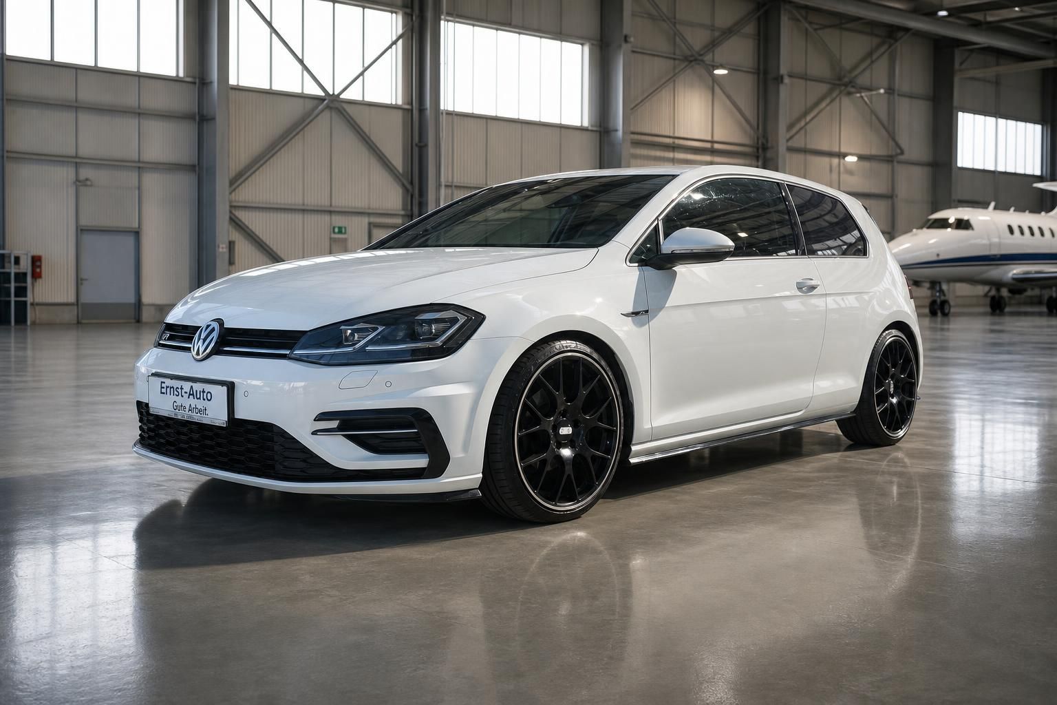 Weißer Volkswagen Golf Frontansicht mit schwarzen Sportfelgen in Fahrzeughalle