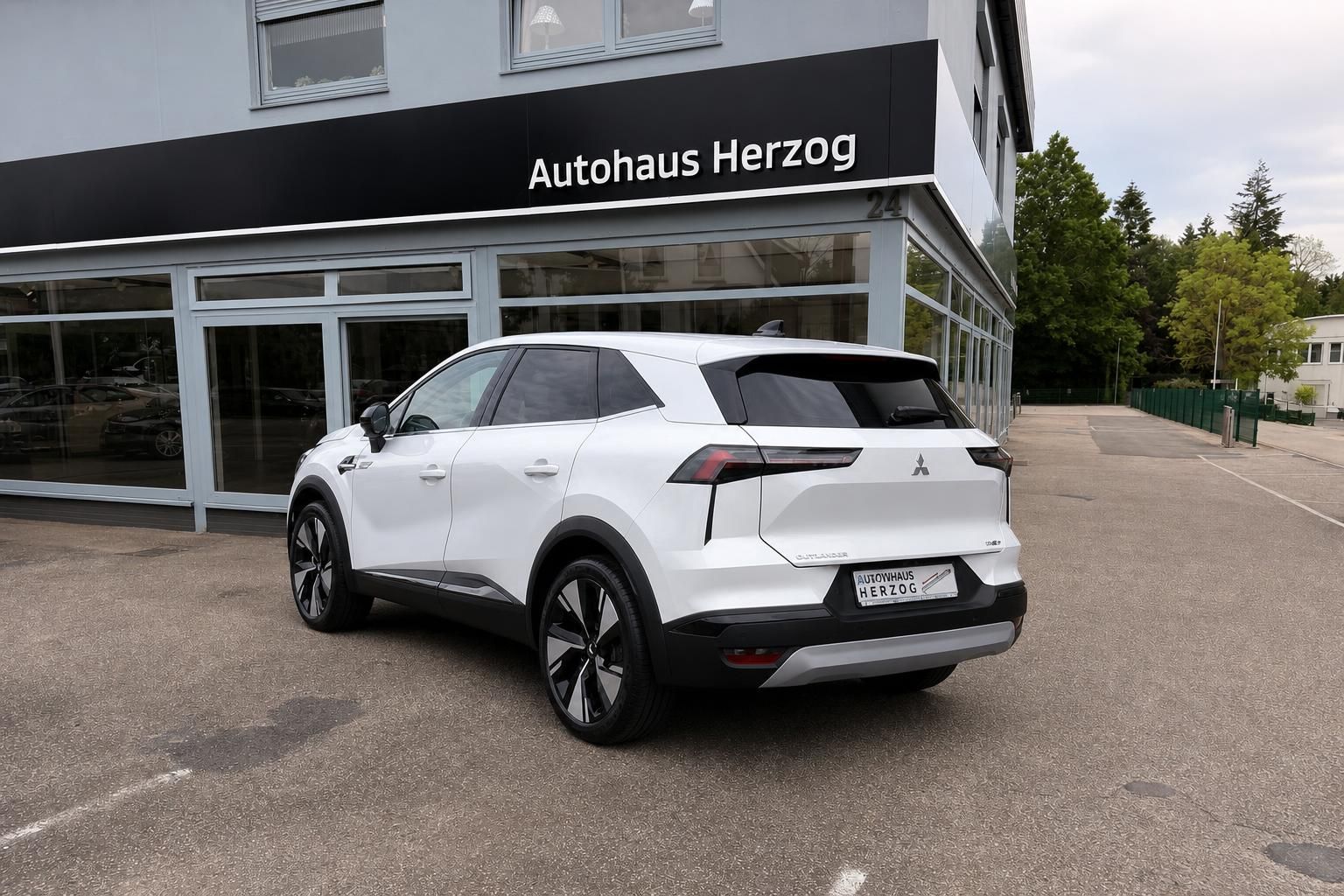 Mitsubishi Outlander in Weiß, Heck-Seitenansicht vor Autohaus