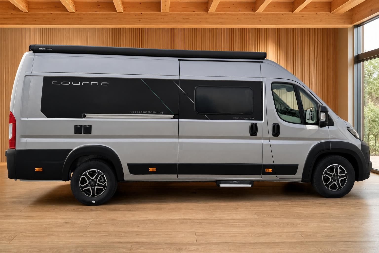 Silberner Tourne Campingbus in Seitenansicht mit Markise und Alufelgen