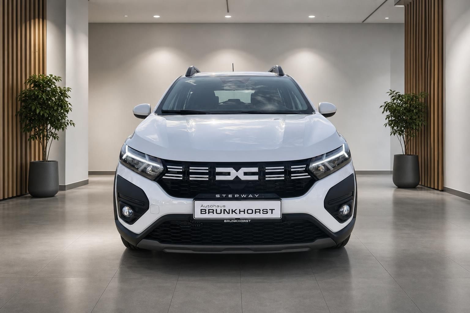 Weißer Dacia Stepway Frontansicht im Autohaus-Showroom mit LED-Scheinwerfern und modernem Design