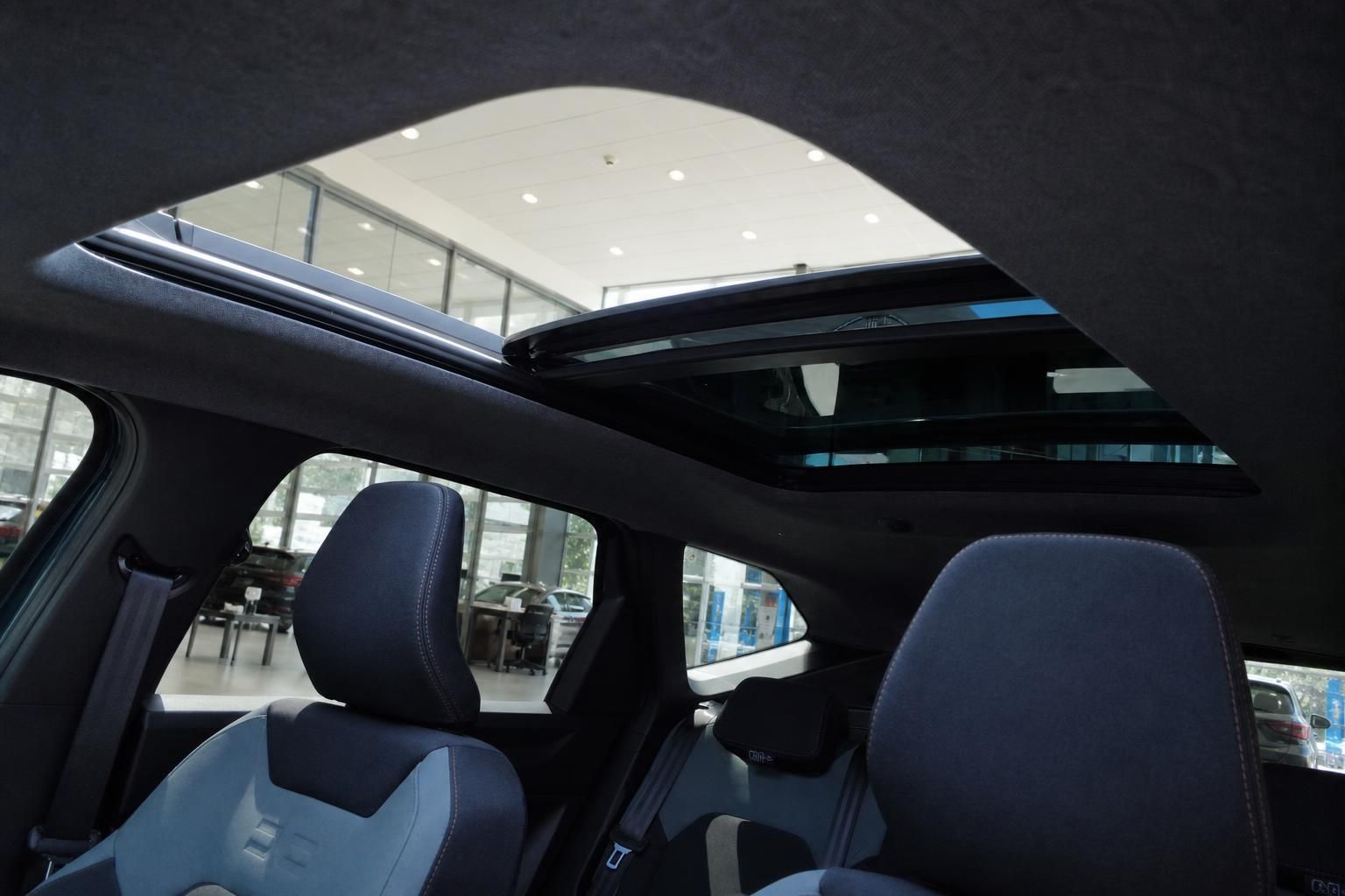 Fahrzeug Innenraum mit geöffnetem Panorama-Glasdach und Stoffsitzen im Autohaus