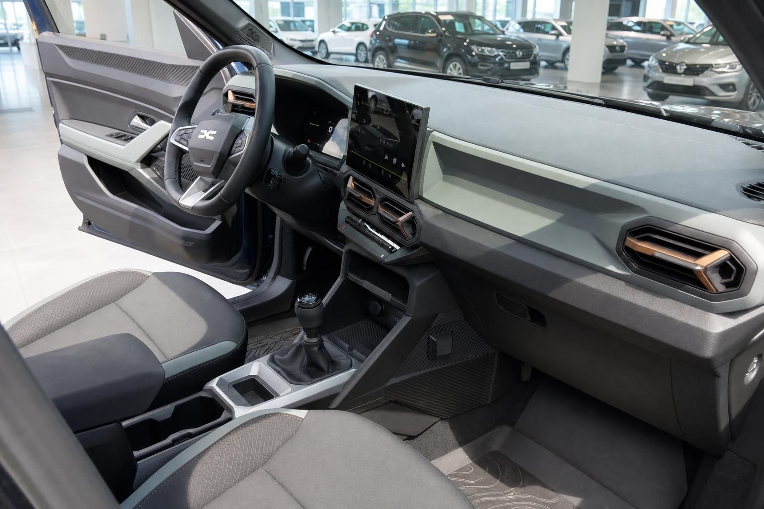 Dacia Innenraum mit Lenkrad, Mittelkonsole, Touchscreen und grauem Armaturenbrett