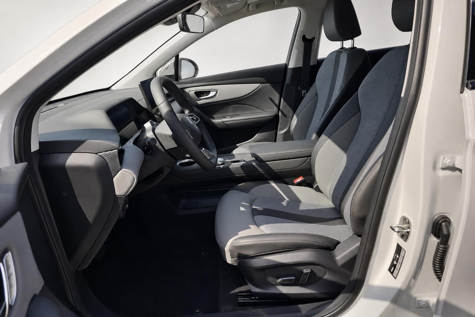 Fahrersitz und Cockpit eines weißen Fahrzeugs mit Lederlenkrad