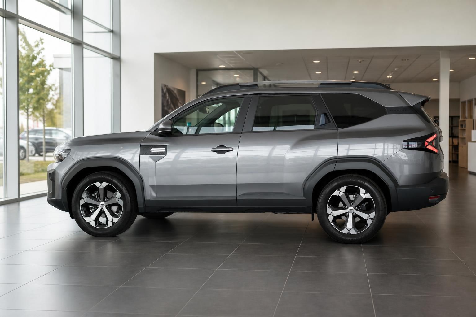 Dacia Bigster grau, Seitenansicht mit Alufelgen im Showroom