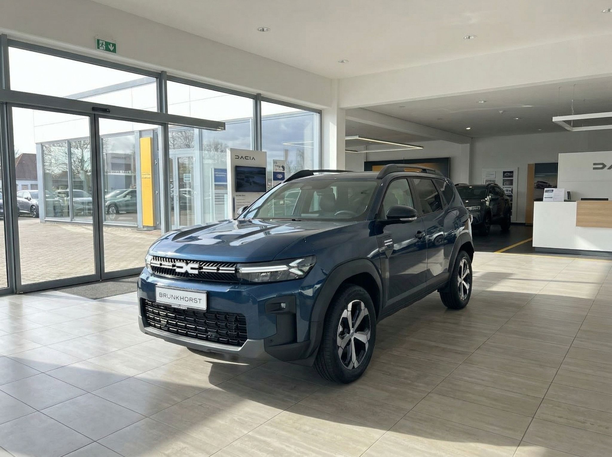 Blauer Dacia SUV in modernem Autohaus-Showroom mit großen Fenstern