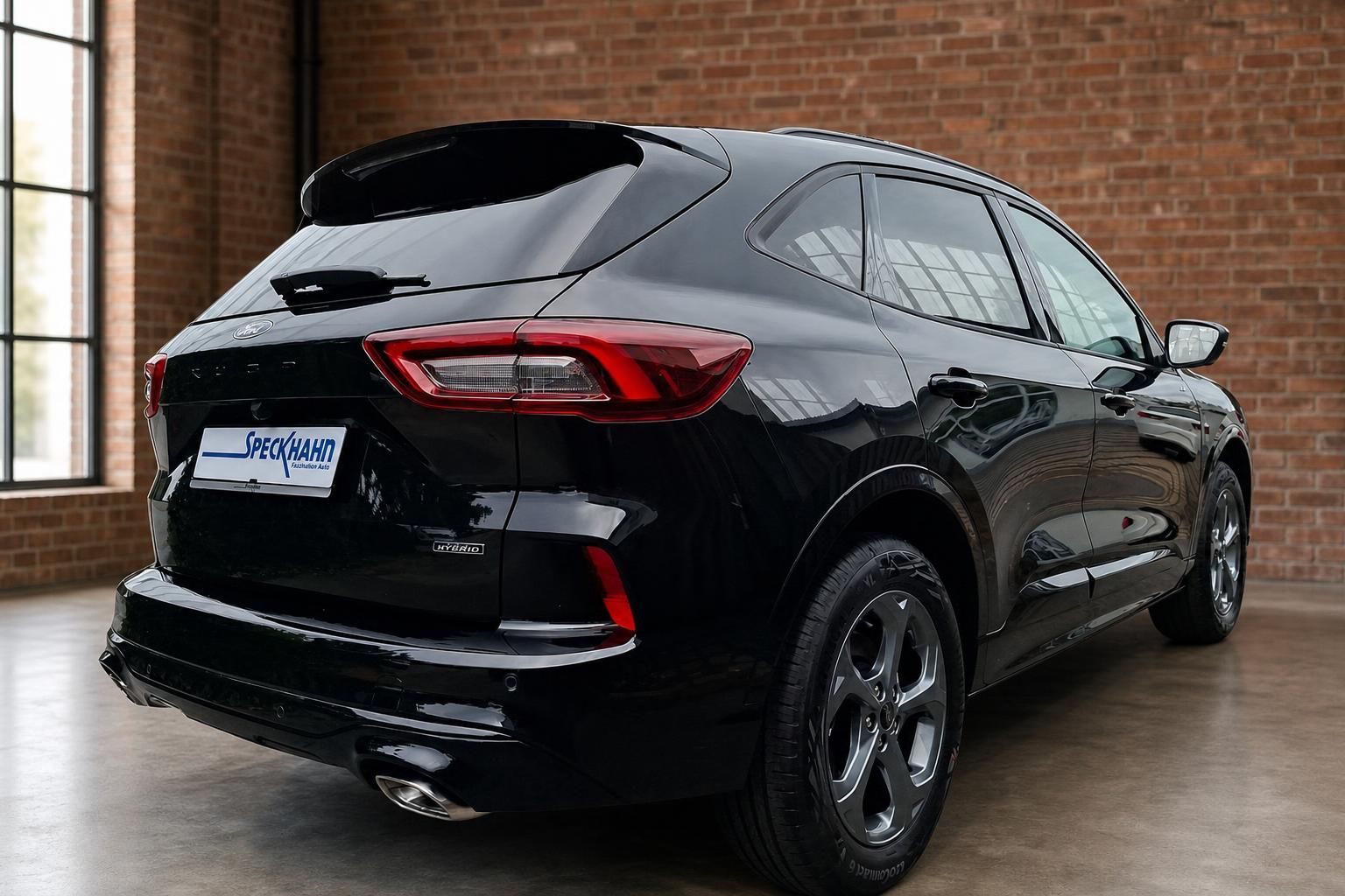 Ford Kuga Hybrid schwarz Heck seitlich vor Backsteinwand