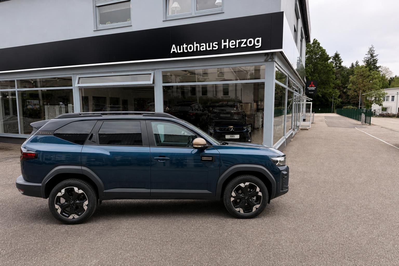 Dacia Jogger blau Seitenansicht vor Autohaus Herzog – SUV mit Dachreling und Leichtmetallfelgen