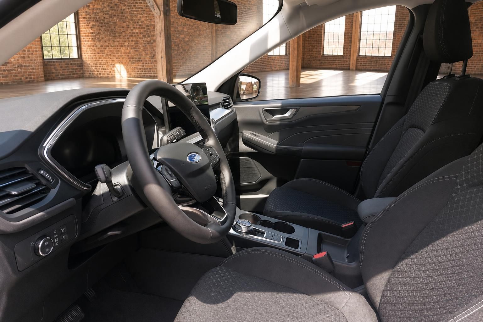 Ford Innenraum Fahrerseite mit Lenkrad, Mittelkonsole und schwarzen Stoff-Vordersitzen