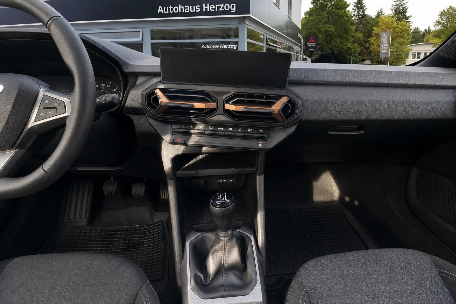 Dacia Duster Innenraum mit modernem Armaturenbrett, Schaltgetriebe und orangenen Designakzenten