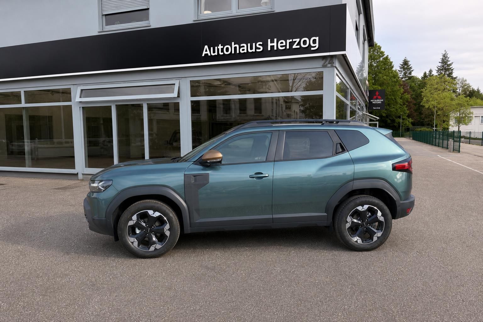 Dacia Duster grün metallic, Seitenansicht - kompakter SUV mit schwarzen Designfelgen und Dachreling