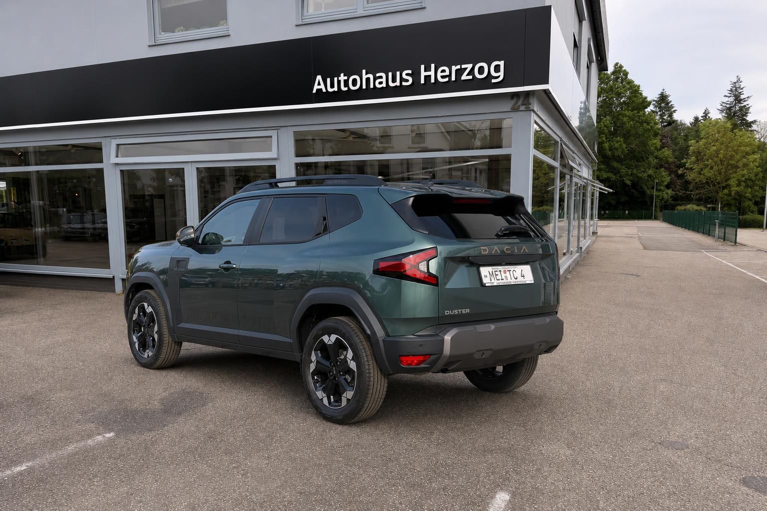 Dacia Duster SUV grün metallic, schräge Heckansicht - kompakter Geländewagen mit Dachreling