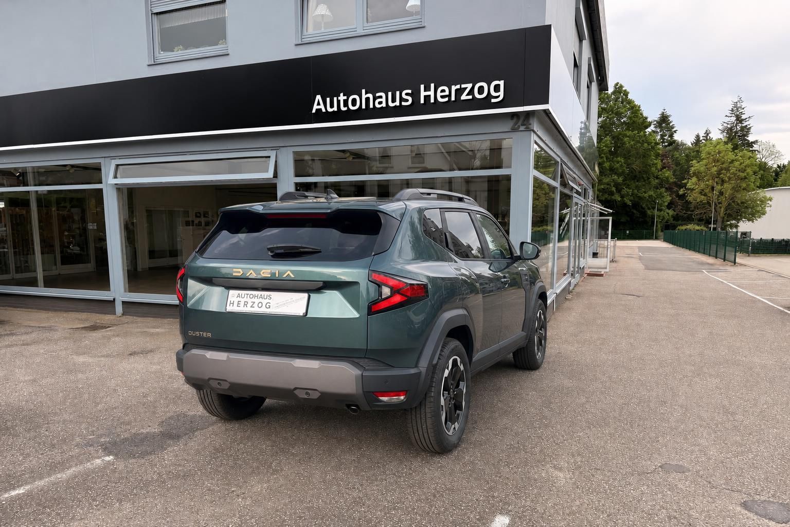 Dacia Duster SUV grün, schräge Heckansicht - Geländewagen mit sportlichen Felgen vor Autohaus Herzog