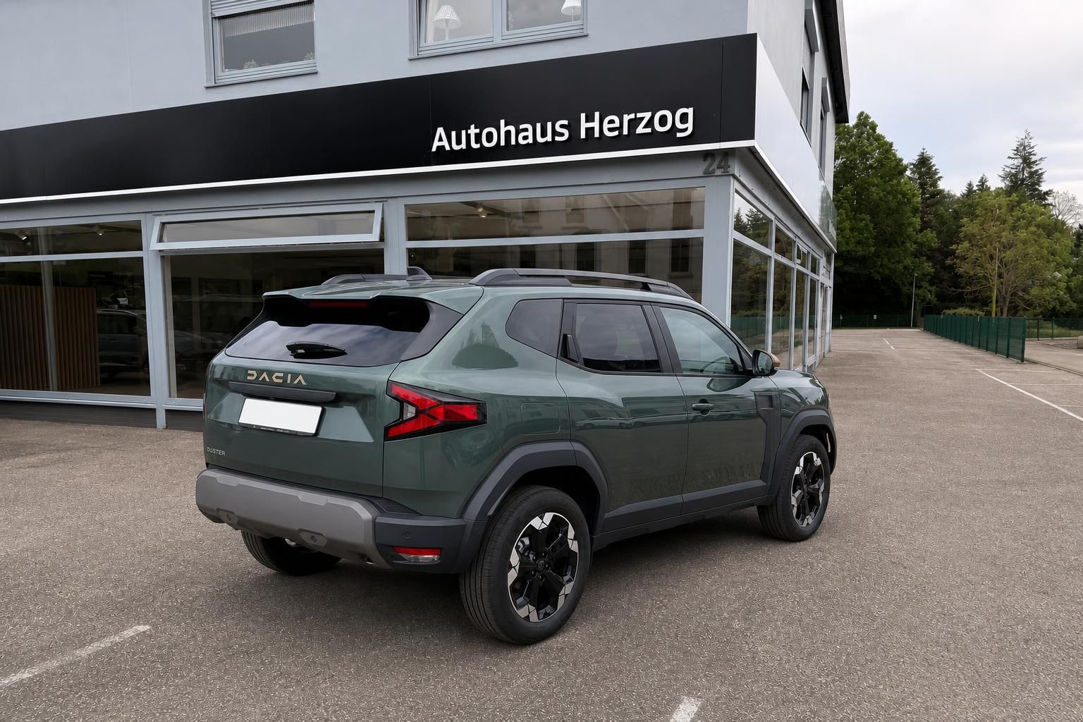 Dacia Duster SUV in grün, Heckansicht vor Autohaus Herzog - Geländewagen mit schwarzen Felgen
