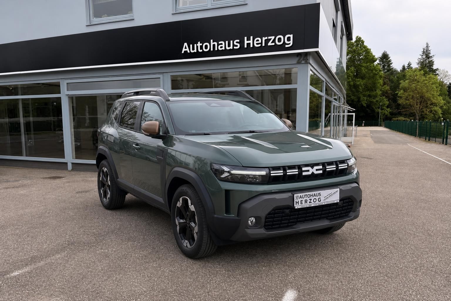 Grauer SUV Dacia vor Autohaus Herzog - Frontansicht des Fahrzeugs