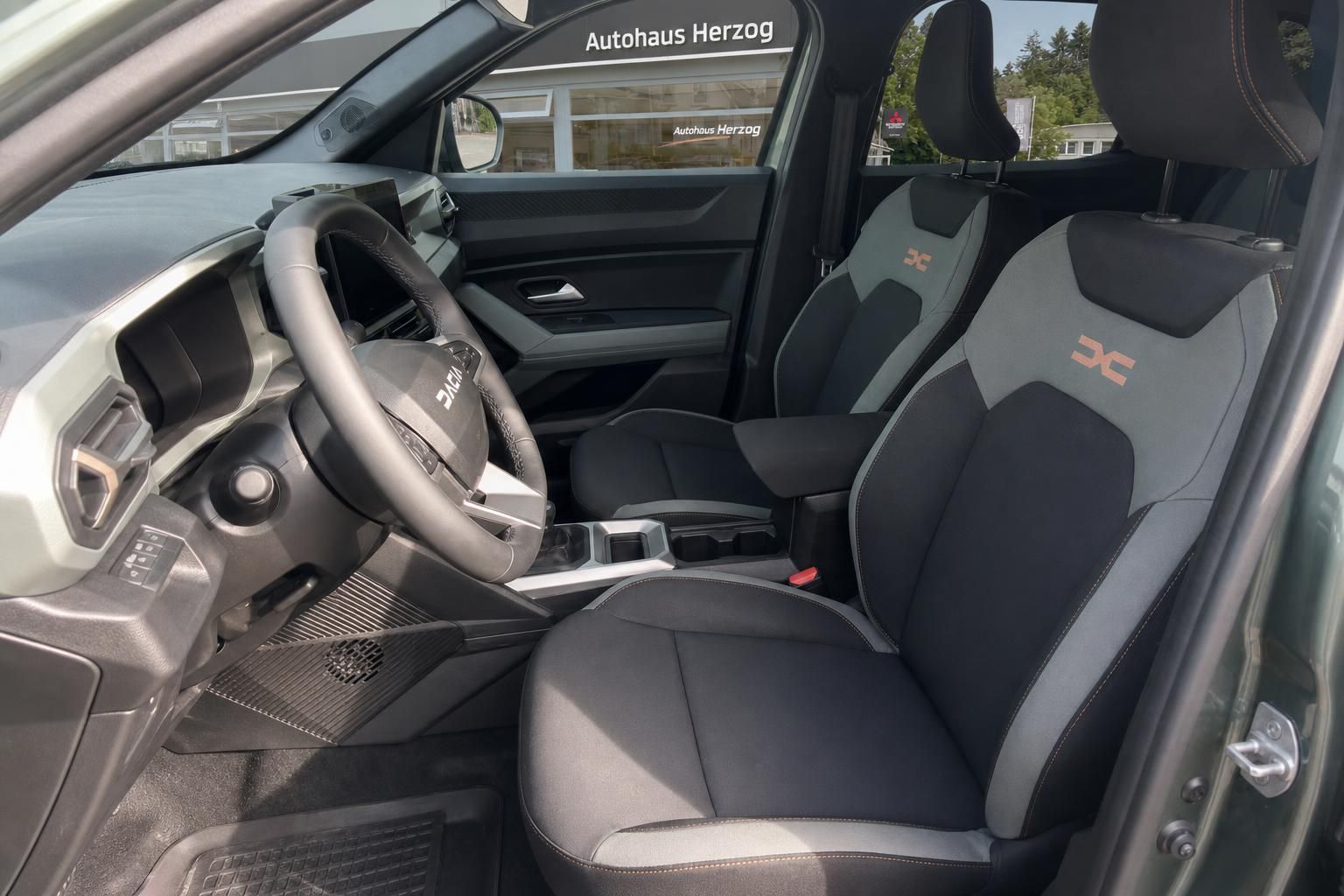 Fahrzeuginnenraum mit schwarzen Sportsitzen und orangenen Akzenten - Detailansicht Cockpit