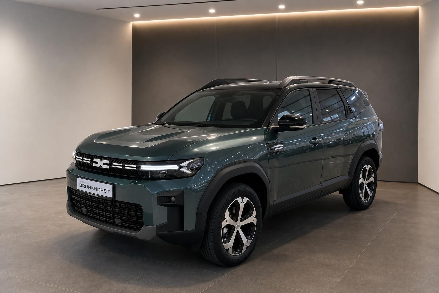 Dacia SUV Seitenansicht in grau-grüner Metallic-Lackierung mit Alufelgen im Autohaus Showroom