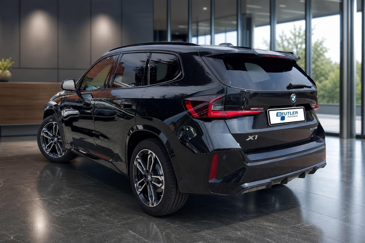 BMW X1 schwarz Heckansicht seitlich vor Glasfassade