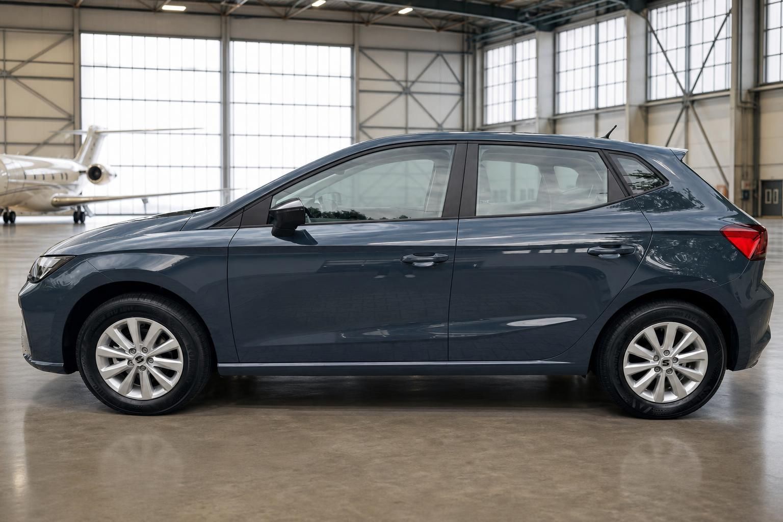 Seat Ibiza Kleinwagen in grau-blau, Seitenansicht in Hangar mit Flugzeug