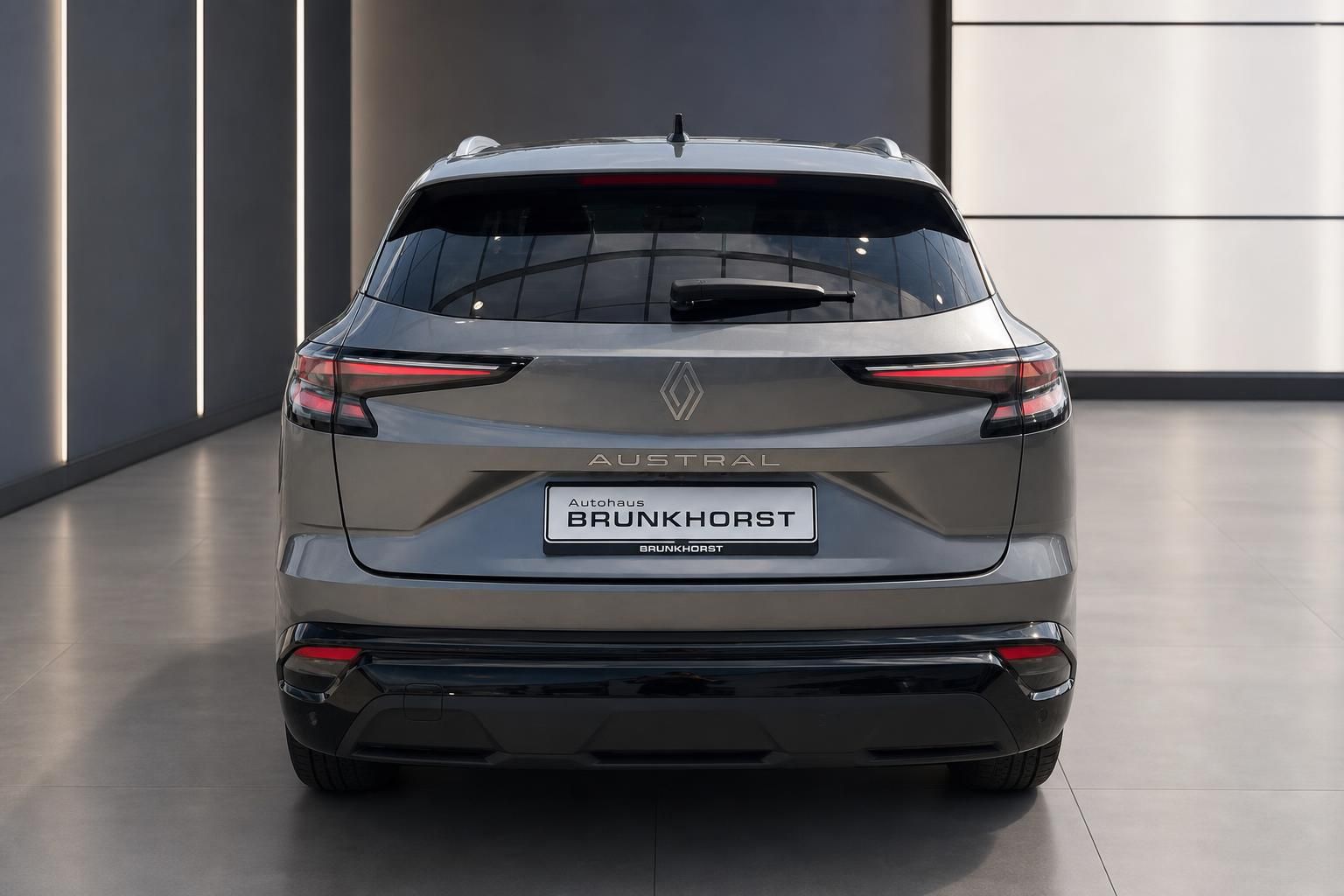 Renault Austral in Grau, Heckansicht in modernem Autohaus-Showroom