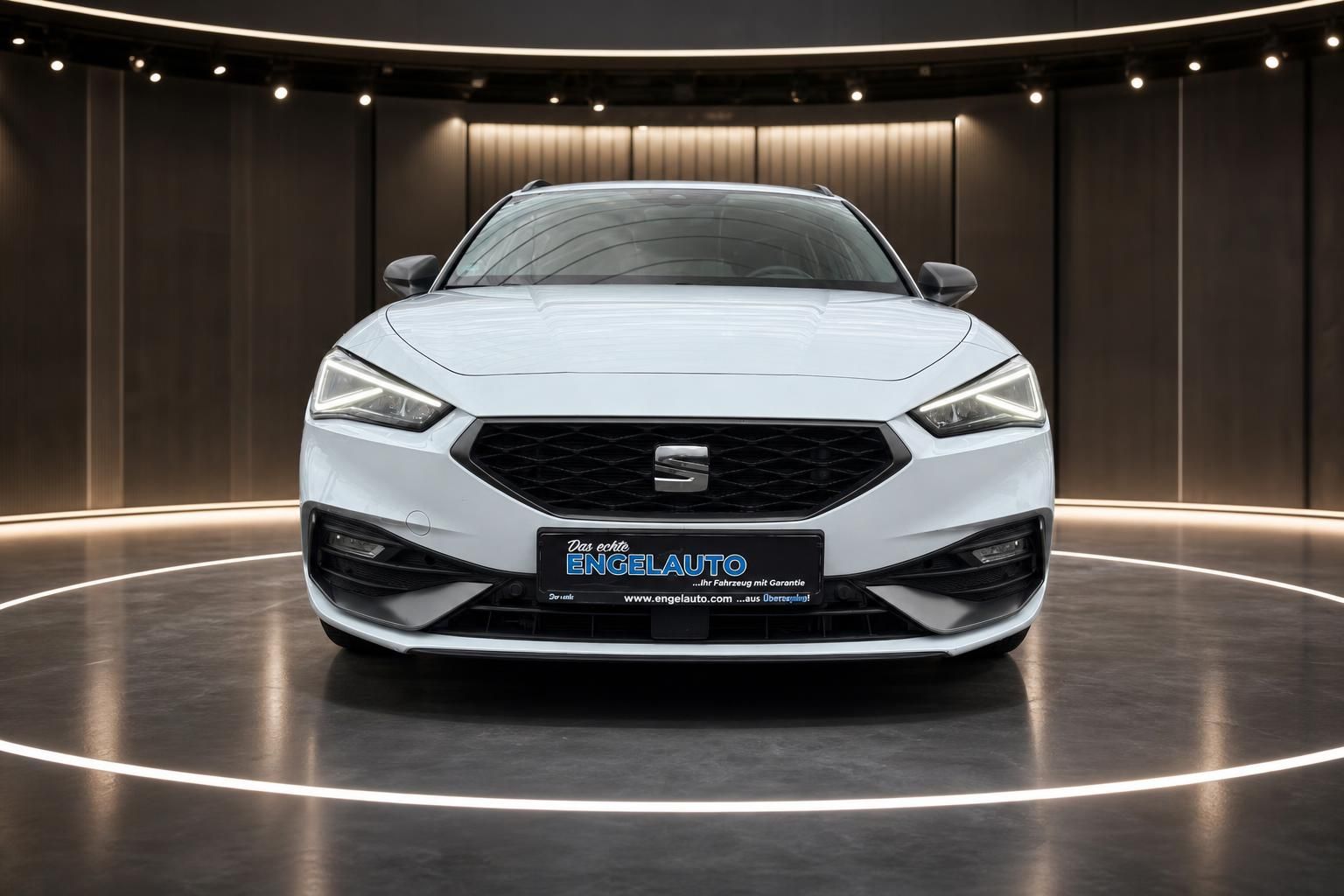 Weißer SEAT Leon Frontansicht im modernen Showroom - Gebrauchtwagen bei ENGELAUTO
