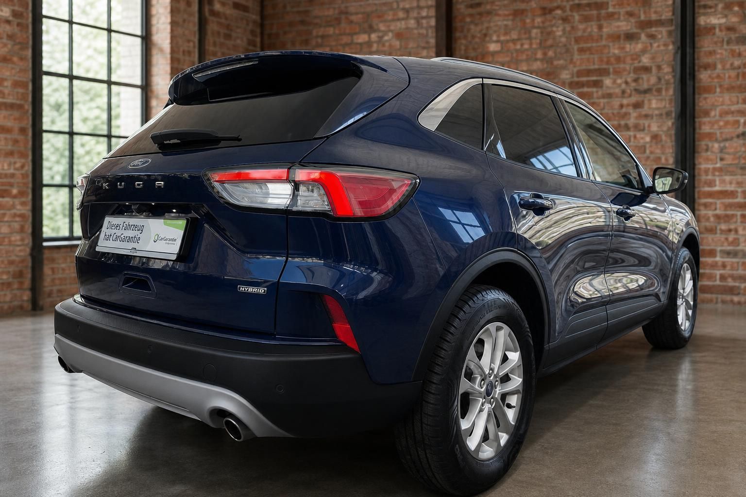 Ford Kuga Hybrid blau Heckansicht schräg mit Alufelgen und Ziegelwand
