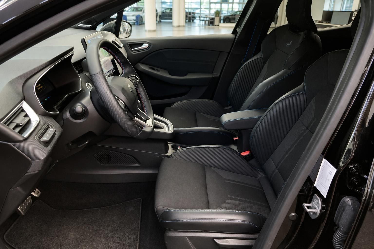 Schwarzes Fahrzeuginterieur mit Sportsitzen, Lenkrad und digitalem Cockpit im Autohaus