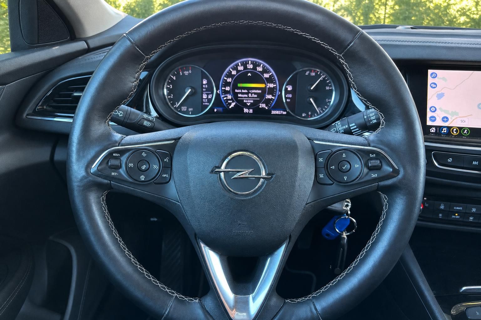 Opel Lenkrad mit Logo und Multifunktionstasten, Blick auf Armaturenbrett und Tachometer