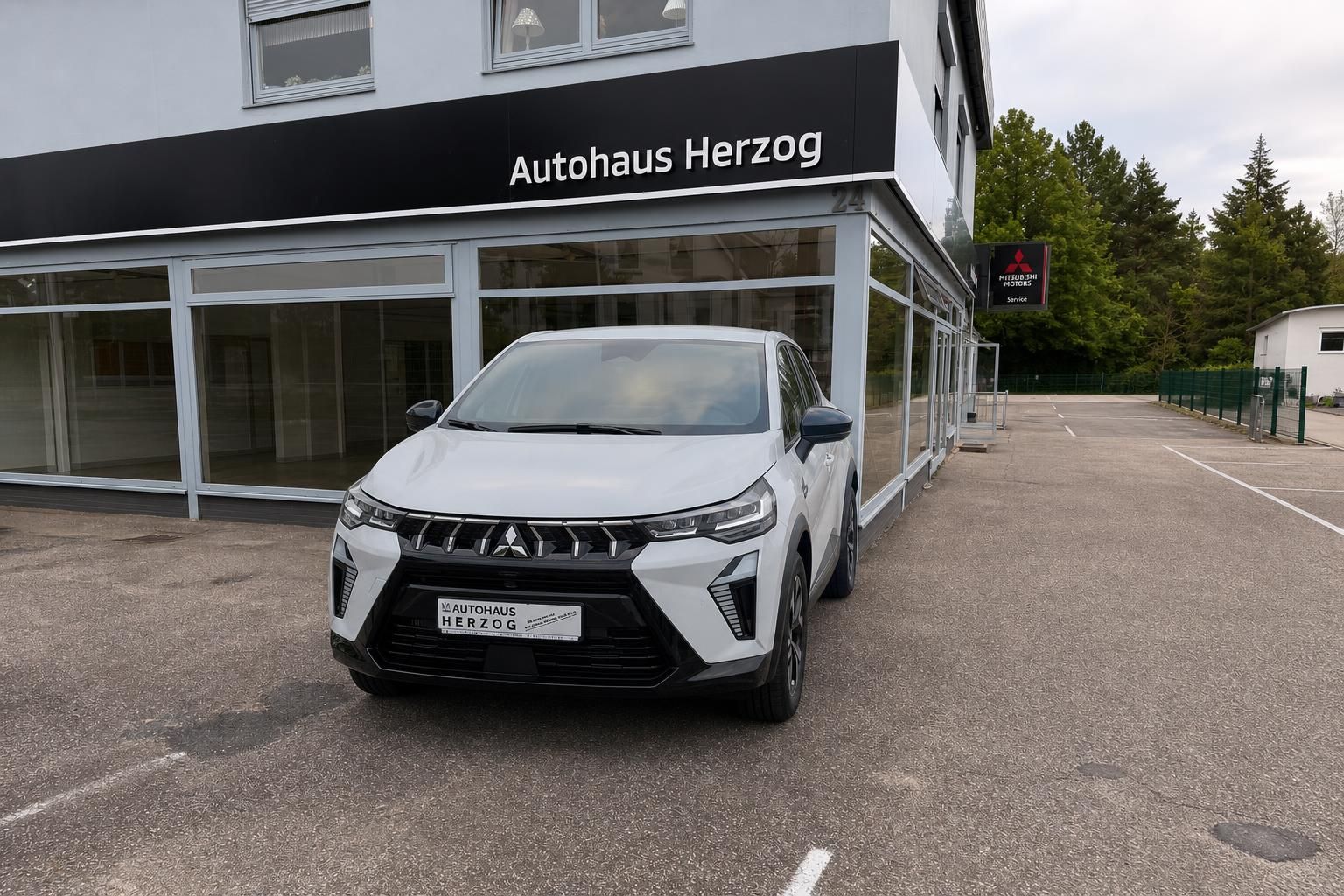 Weißer Mitsubishi SUV Frontansicht vor Autohaus Herzog Gebäude